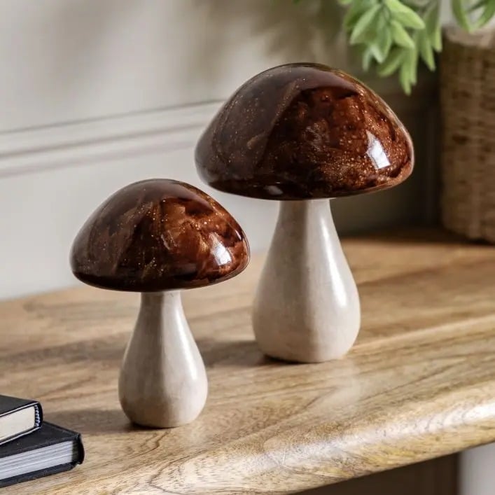 Set of two brown and cream mushroom ornaments styled on wooden console table with books and greenery – decorative home accessories.