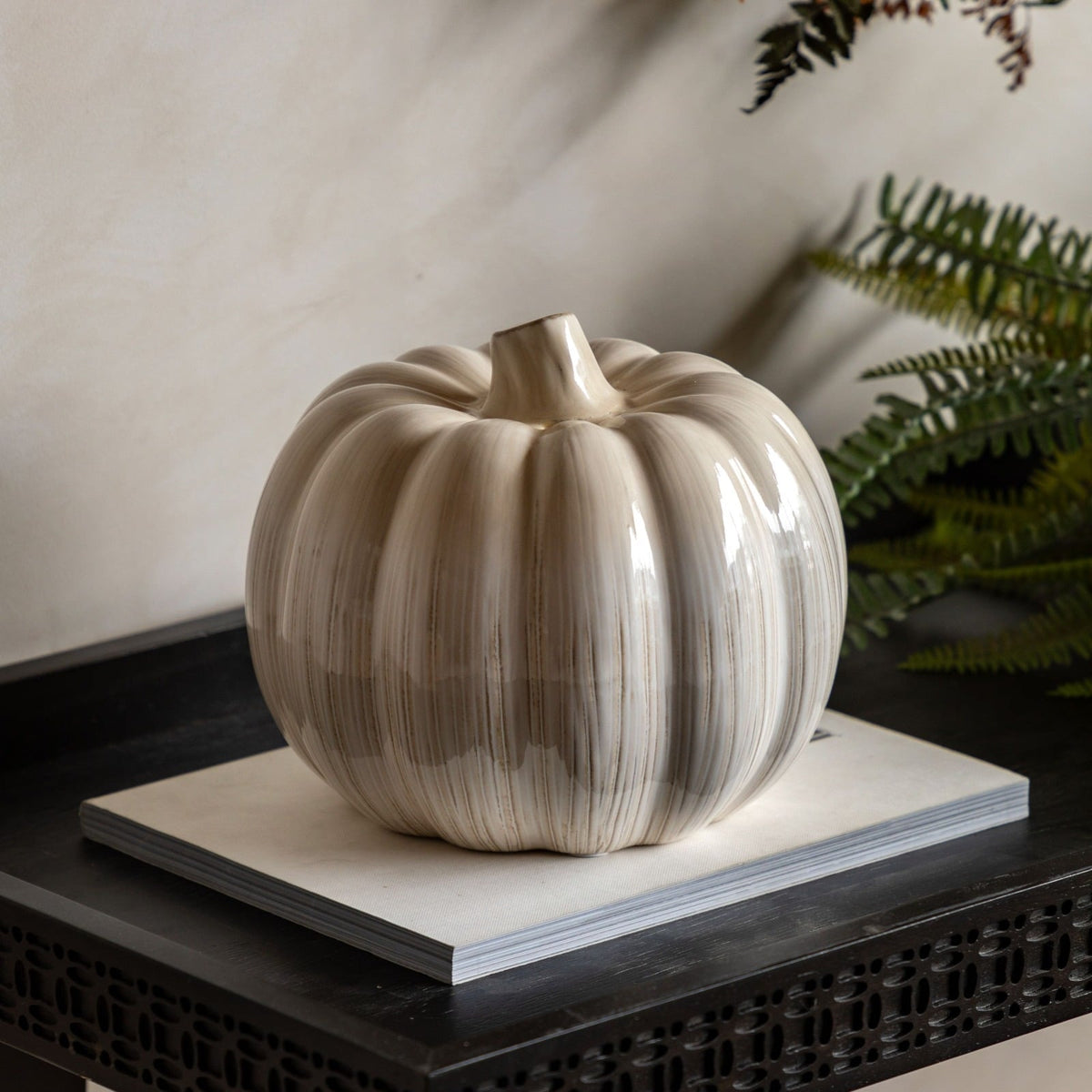 Cream ceramic pumpkin ornament styled on console table with green pumpkin and autumn wreath for fall décor inspiration..