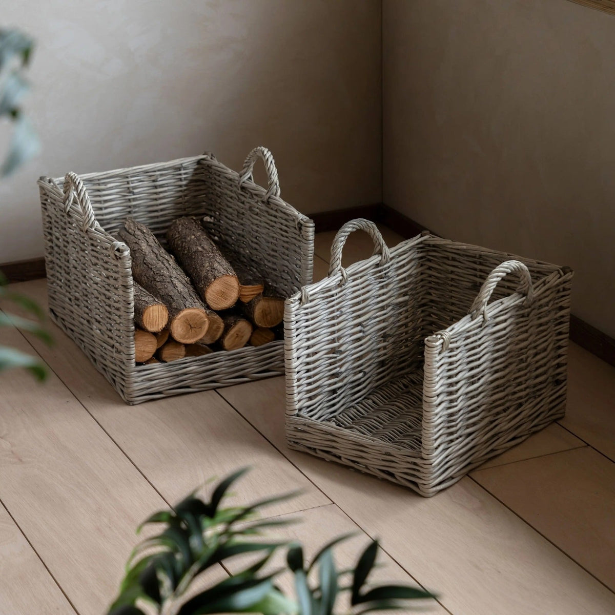 Set of grey wicker log baskets with handles, styled in a modern living room, perfect for firewood or storage.