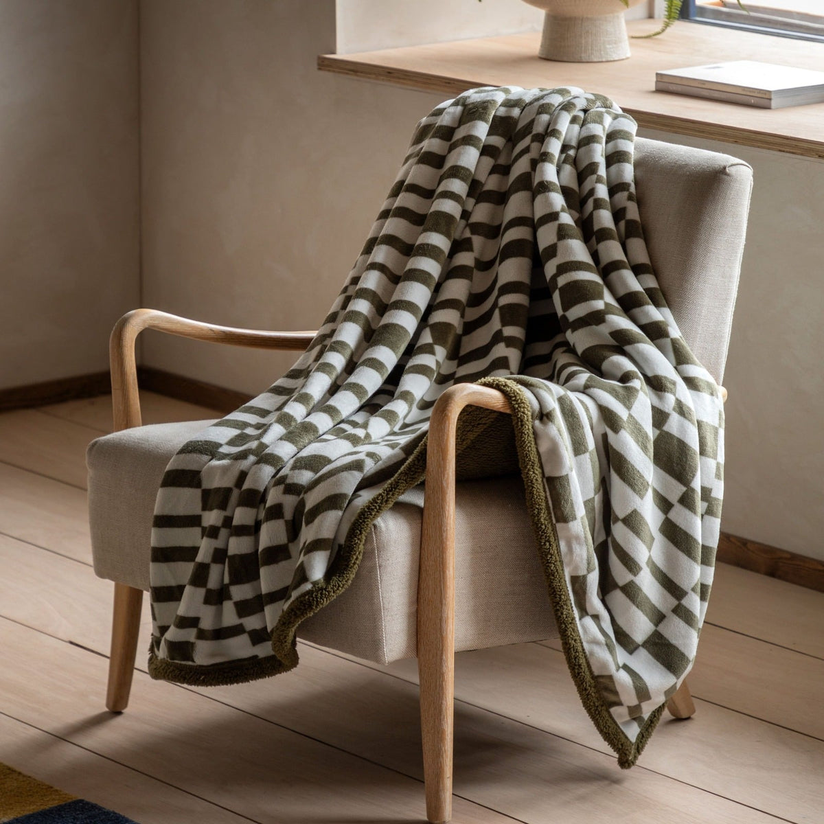 Folded olive green geometric striped throw blanket with soft fleece texture and decorative edging.