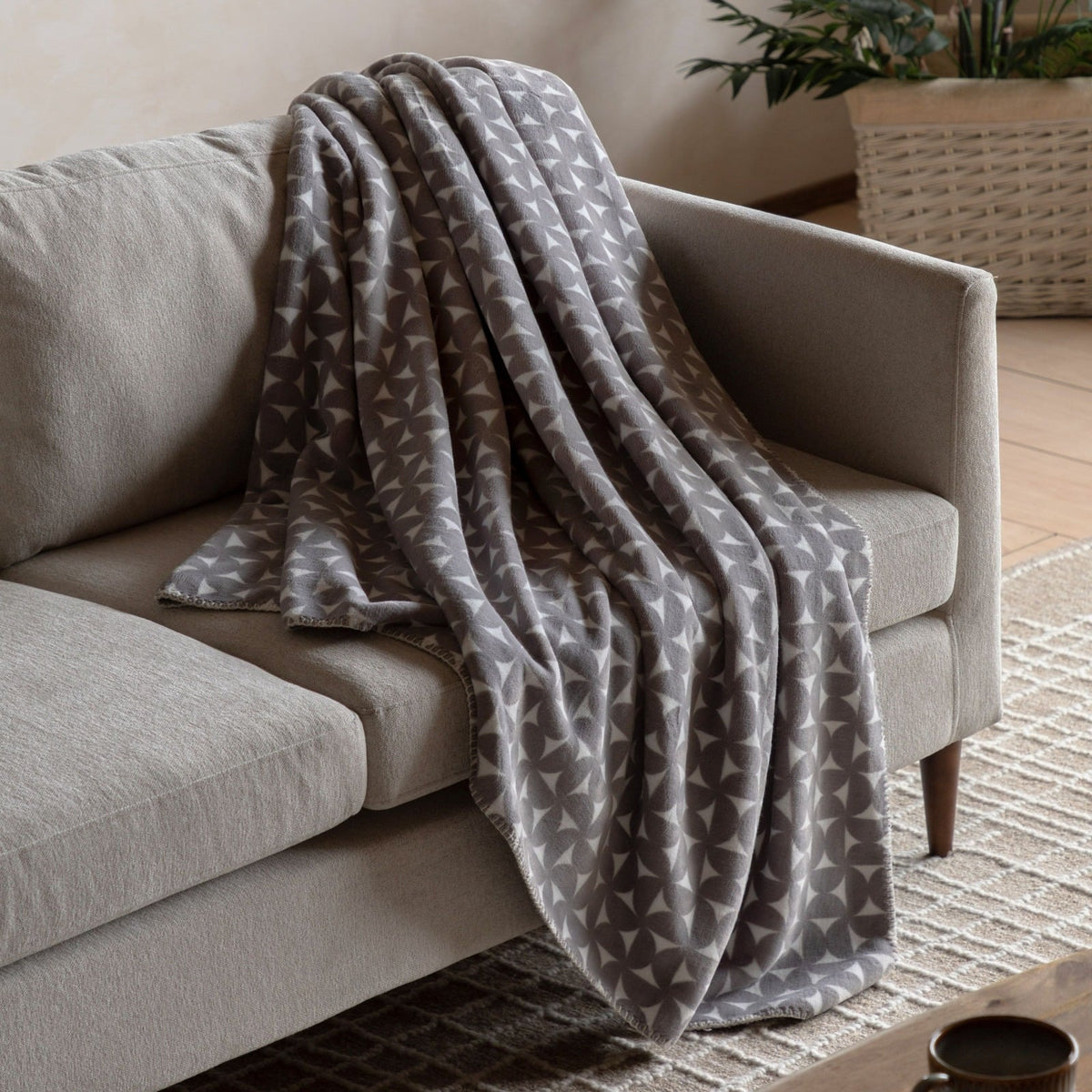 Geometric design detail on soft grey fleece throw for modern interiors.