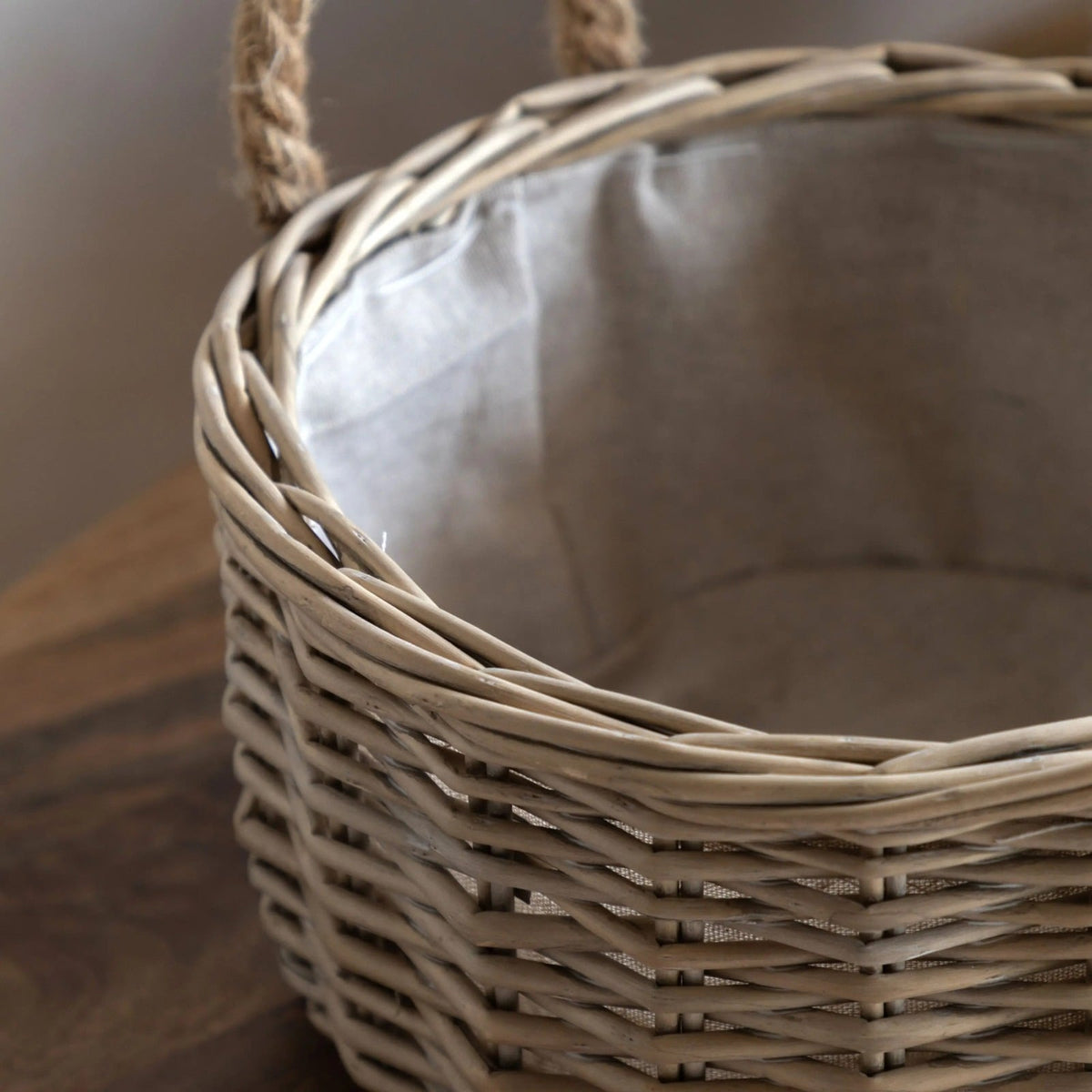 Close-up of wicker storage basket with rope handles and linen lining, highlighting natural woven texture.