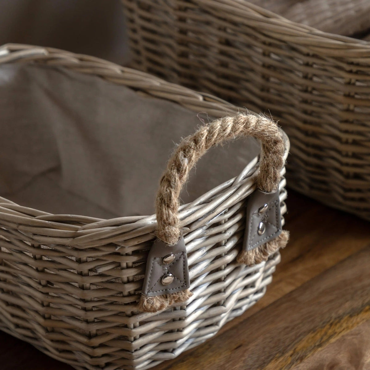 Close-up of wicker basket detail with sturdy rope handle and linen fabric lining for rustic home storage.